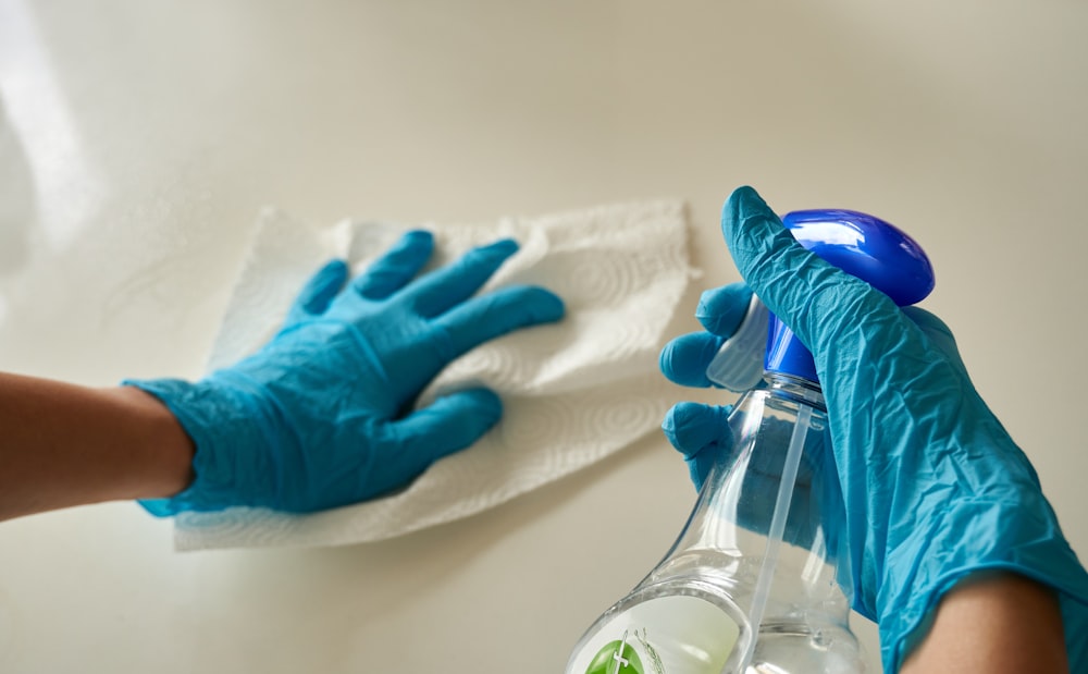 Gloved hands wiping a surface with spray — detail cleaning